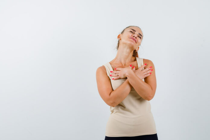young-girl-holding-hands-crossed-chest-beige-top-black-pants-looking-pretty-front-view hidradenite