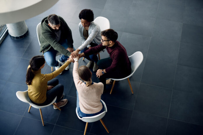 Above view of group therapy participants holding hands in unity Alcoólicos Anônimos
