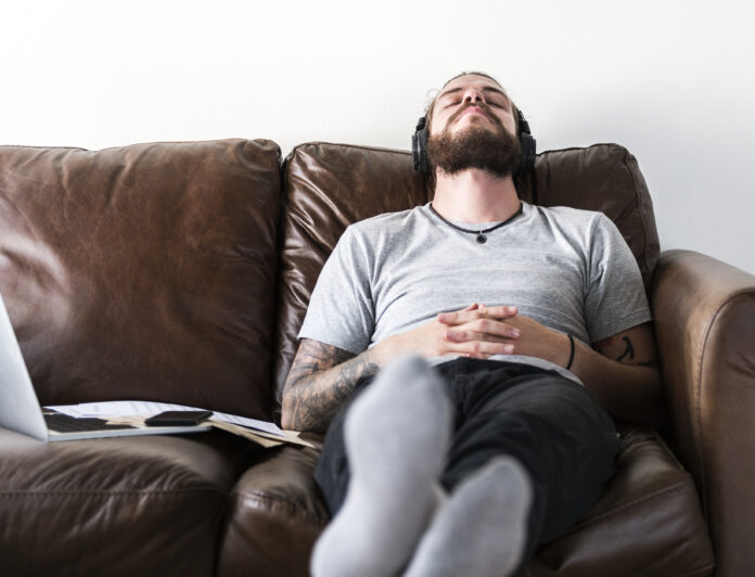 Caucasian man taking a break from work by listening to music sair do sedentarismo